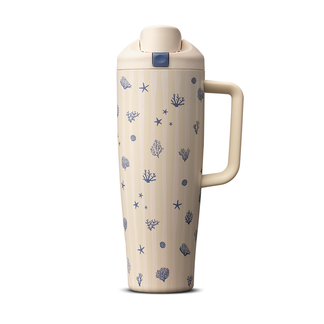 Owala Birthday Bash Coral Cabana 30oz FreeSip Tumbler; cream body with subtle vertical stripes scattered with small navy blue seashells, starfish, coral, and sea urchin illustrations, matching cream flip cap, lid, and side handle