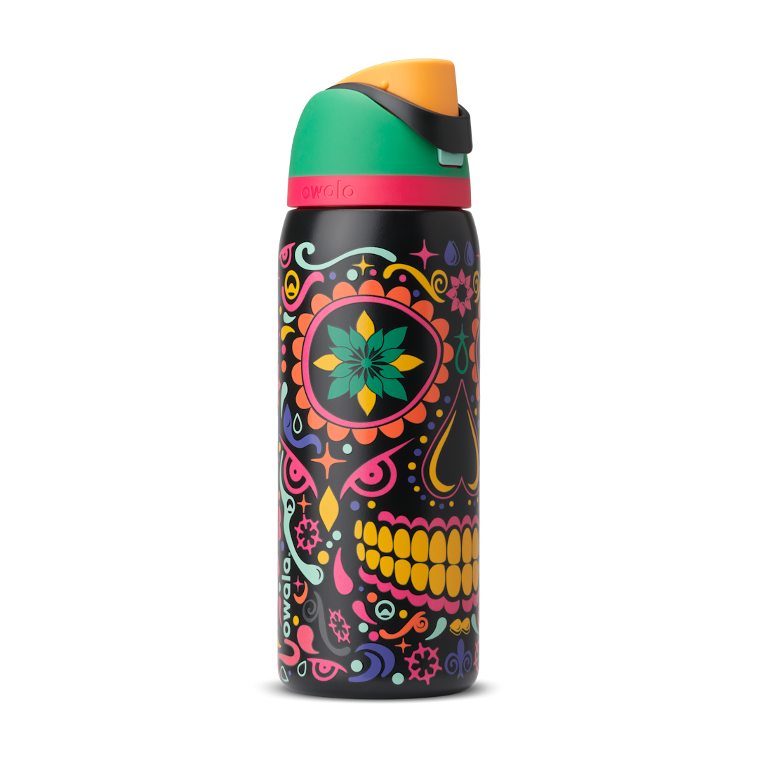 FreeSip 32oz in Sugar Skull, black body with colorful Day of the Dead sugar skull graphic in pink, yellow, green, and turquoise; green flip cap with orange detail, hot pink accent band on the lid; glows in the dark