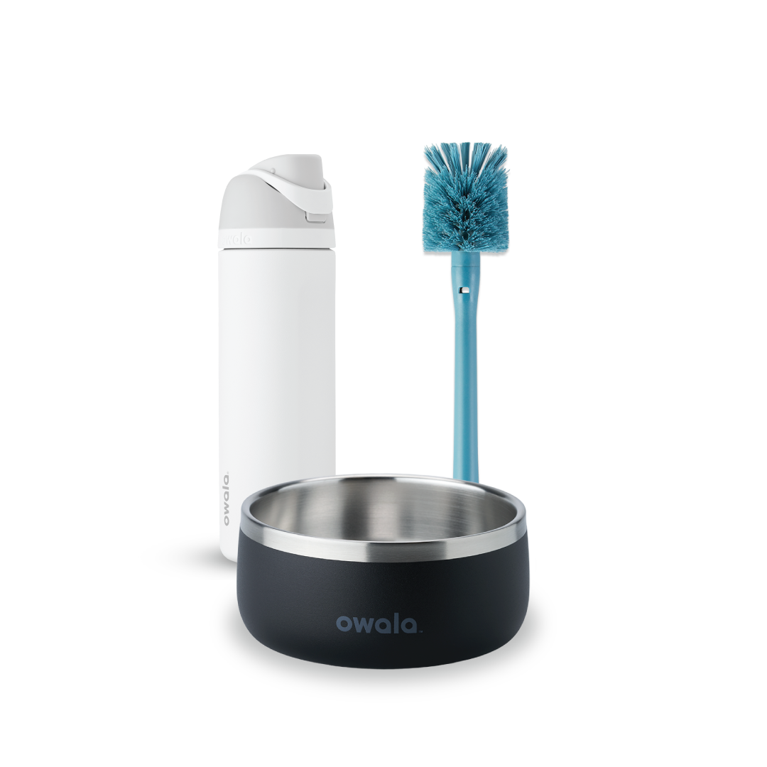 Owala FreeSip and Pet Bowl Bundle showing a white FreeSip bottle, a teal-handled bottle brush with blue bristles, and a dark charcoal stainless steel pet bowl with white Owala logo